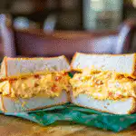 Homemade pimento cheese sandwich cut in half, creamy filling with diced pimentos on soft white bread, inspired by the Masters