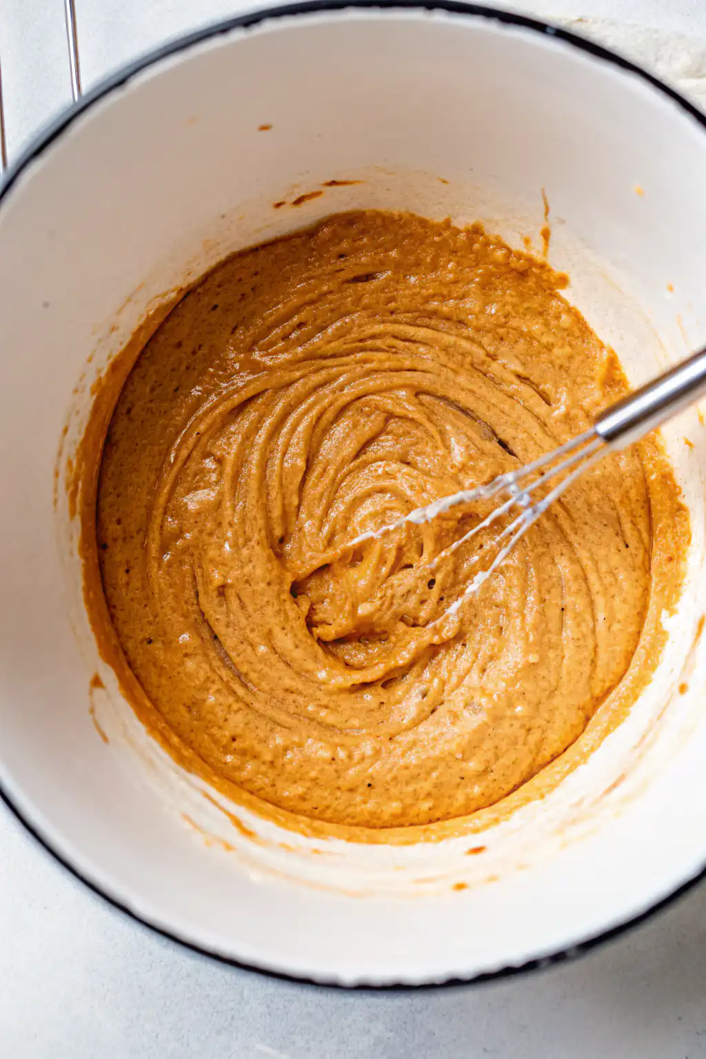Peanut butter and maple syrup mixture in a mixing bowl with whisk