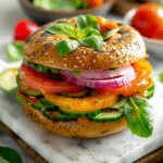 Finished veggie bagel with recipe card on white marble