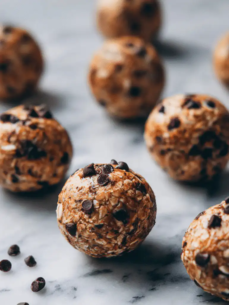 Peanut butter oatmeal desserts energy balls with mini chocolate chips scattered on marble surface.