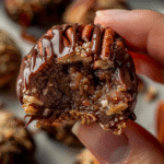 Close-up of a no bake pecan pie ball dipped in chocolate with pecan inside.