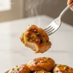Close-up of a fork lifting a piece of honey teriyaki chicken.