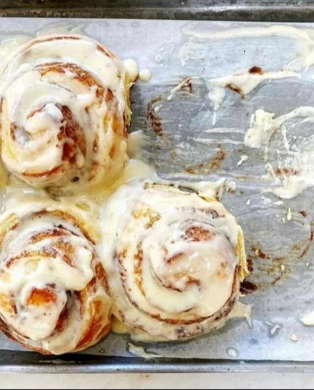 Deliciously soft and gooey cinnamon rolls drizzled with icing on a plate.