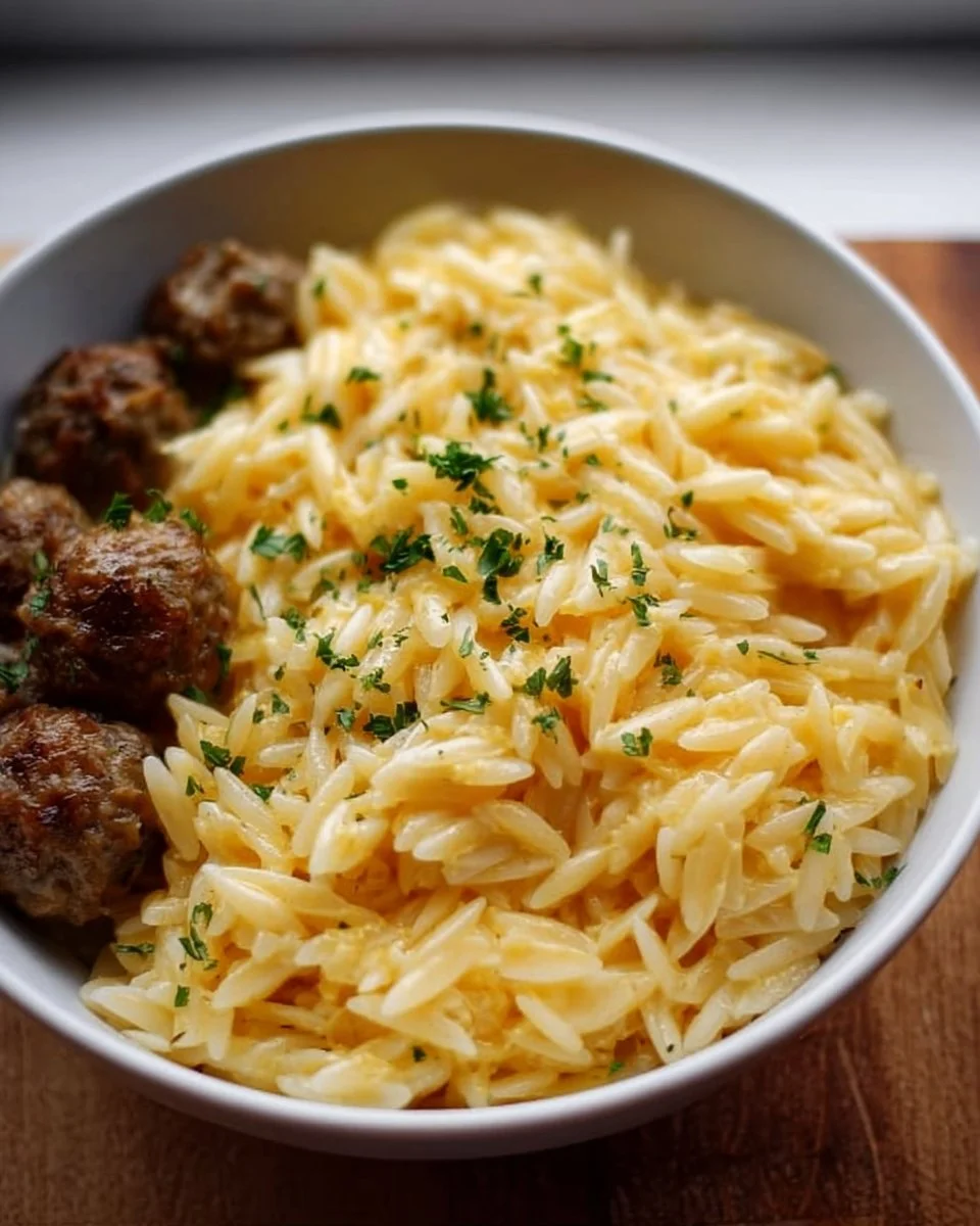 Cheesy orzo pasta dish garnished with herbs and cheese