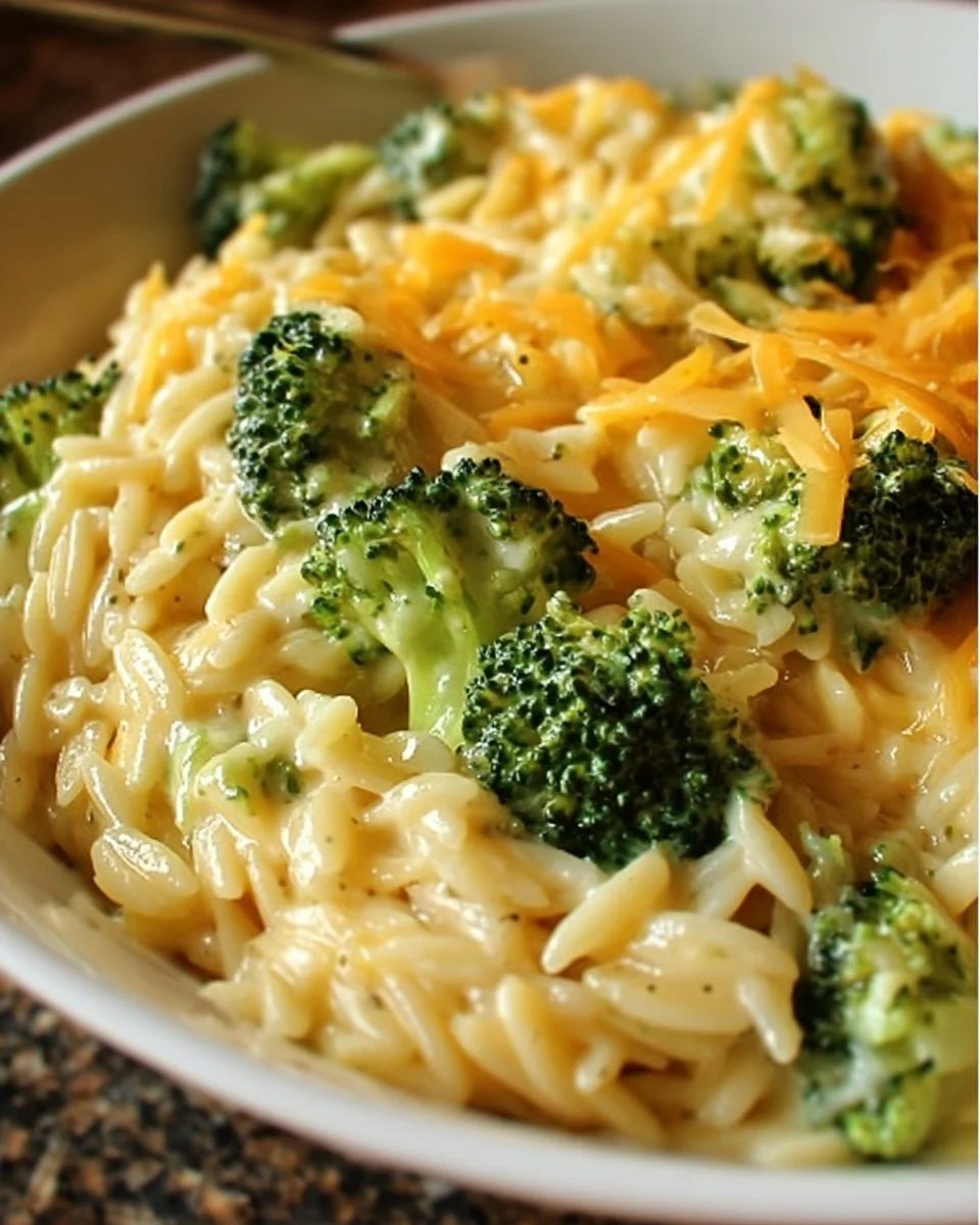 Creamy one-pot broccoli cheddar orzo dish topped with fresh broccoli and cheese